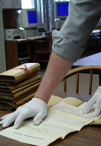 Hands in white gloves spreading a document on a tabletop
