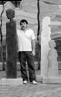 Photo of the artist Bobby Falwell standing with his "Kentucky Woods" sculpture